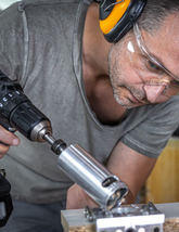 Man using a power drill in a workshop setting