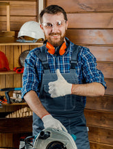 Man in a workshop giving a thumbs-up with a circular saw in front of him.