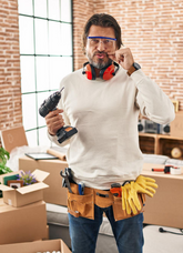 Man in a room with moving boxes, tools, and safety goggles.