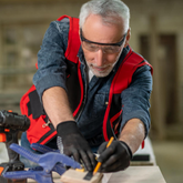 Man working with tools on a wooden surface in a workshop setting
