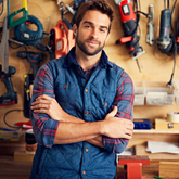Man standing in a workshop with tools on the wall
