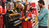 Employee in a hardware store assisting a customer with tools